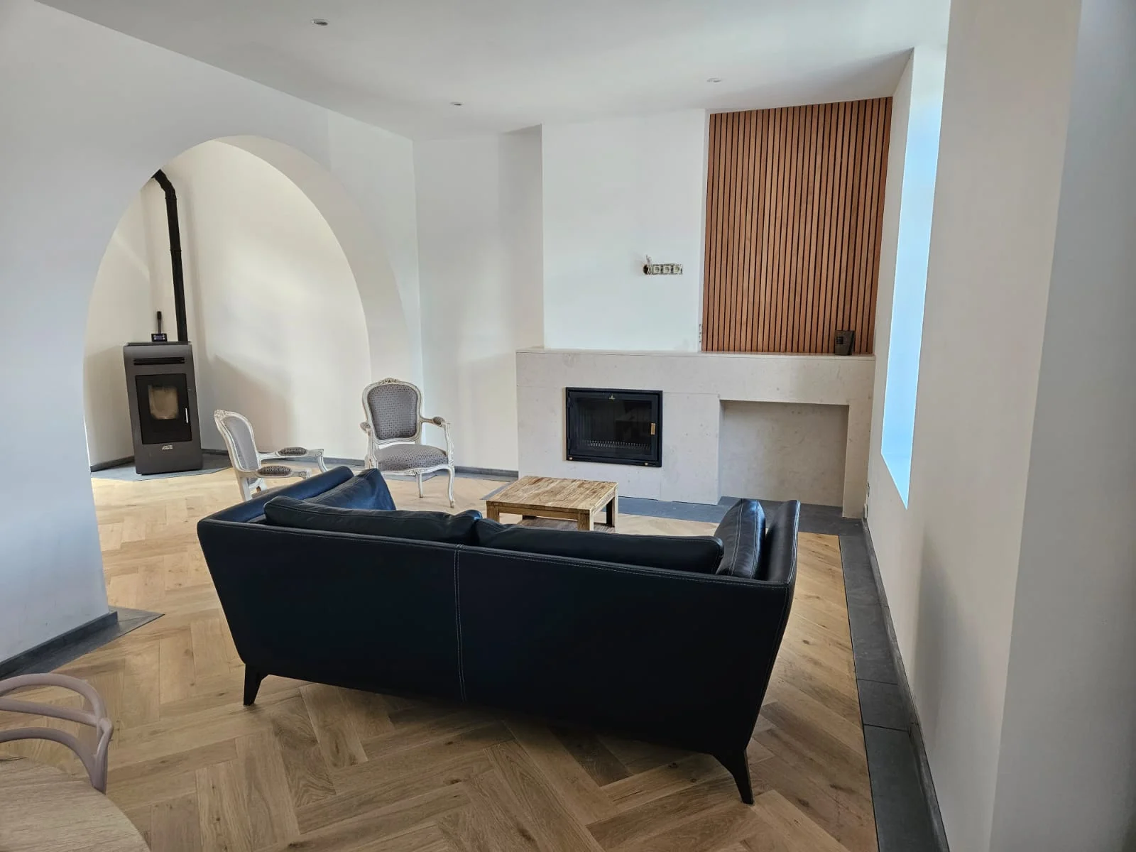 Salon rénové à Ligne avec canapé vu de dos, cheminée et menuiserie décorative