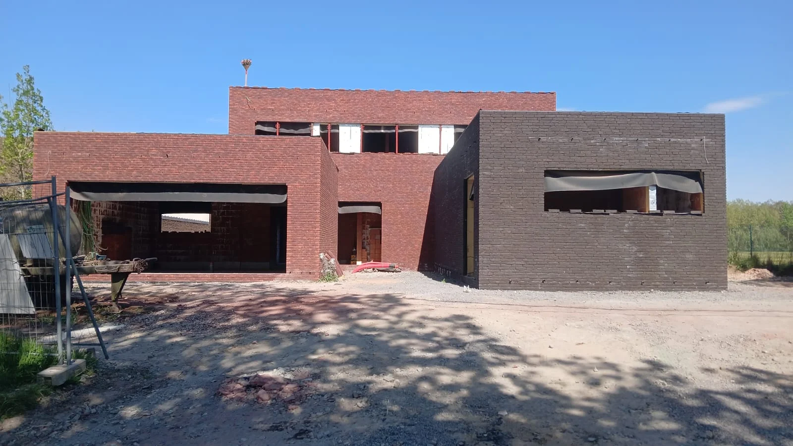 Vue d’ensemble du gros œuvre de la maison à Ostiches, en briques rouges et sombres